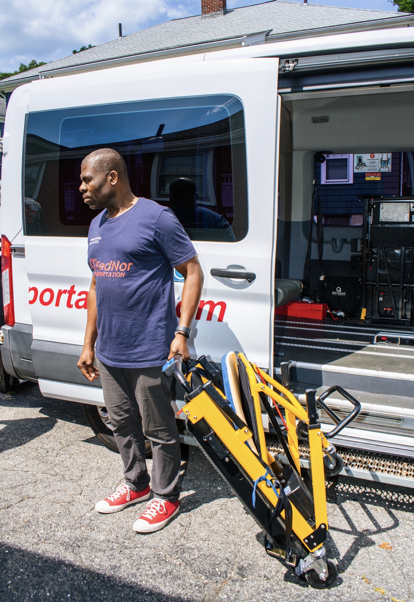 FedNor driver beside a van with a folded stair chair