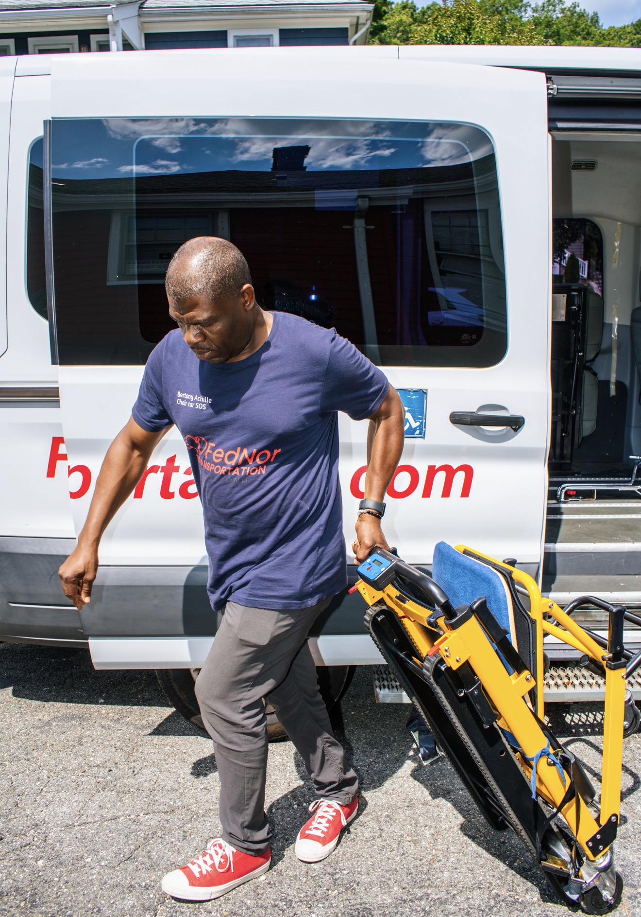 FedNor driver carrying a folded powered stair chair to the van