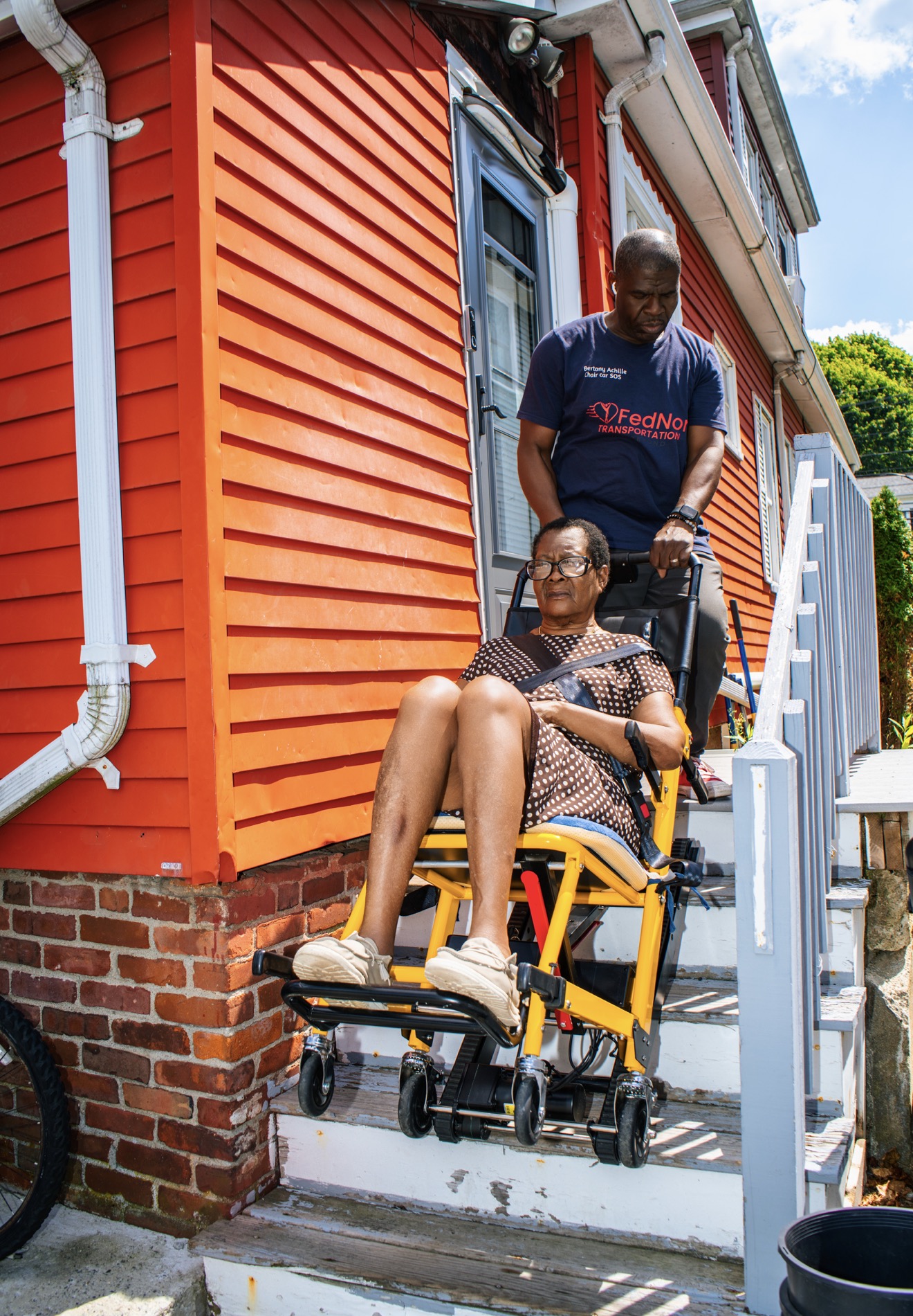FedNor driver bringing a passenger down front steps in a stair chair