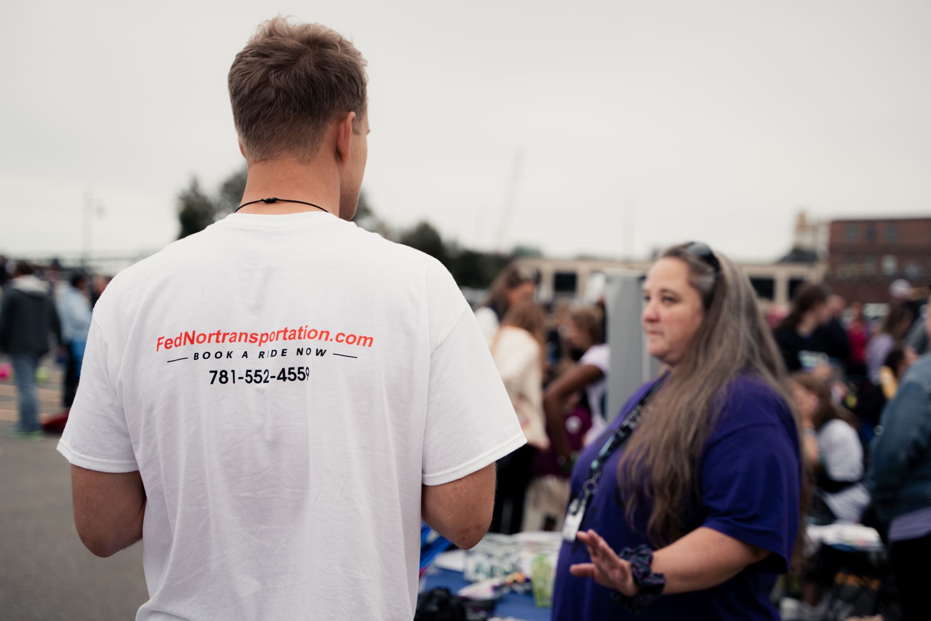 FedNor team member in branded shirt connecting with community member at outreach event