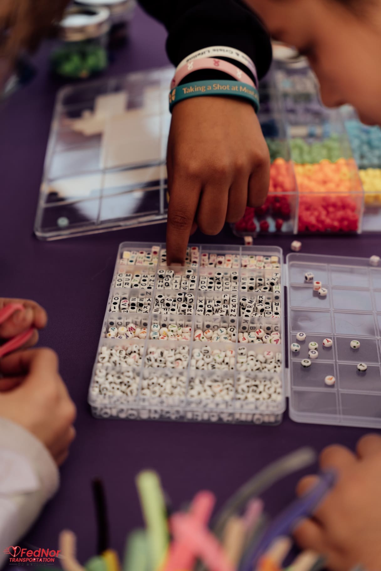 Child making a beaded bracelet at the Best Buddies craft table